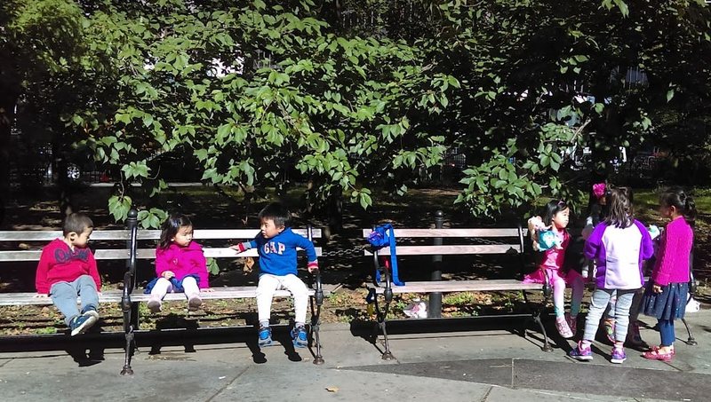 Children sitting on benches in a downtown park