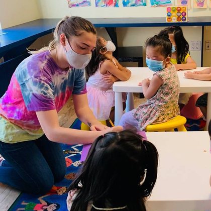 A teacher helping children at an art table