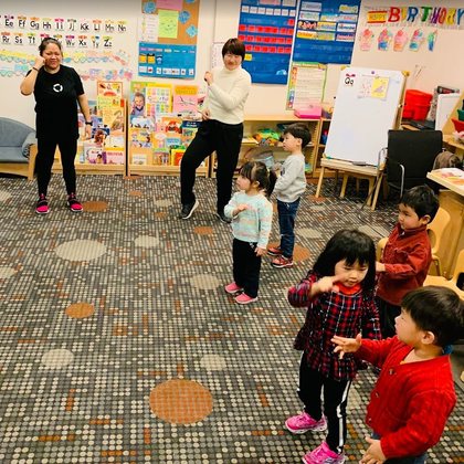 Teachers leading children in a music and movement activity
